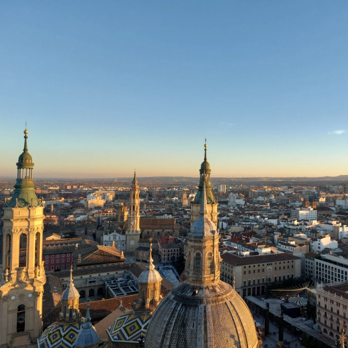 Vista a&eacute;rea de una ciudad con una catedral y edificios al atardecer.