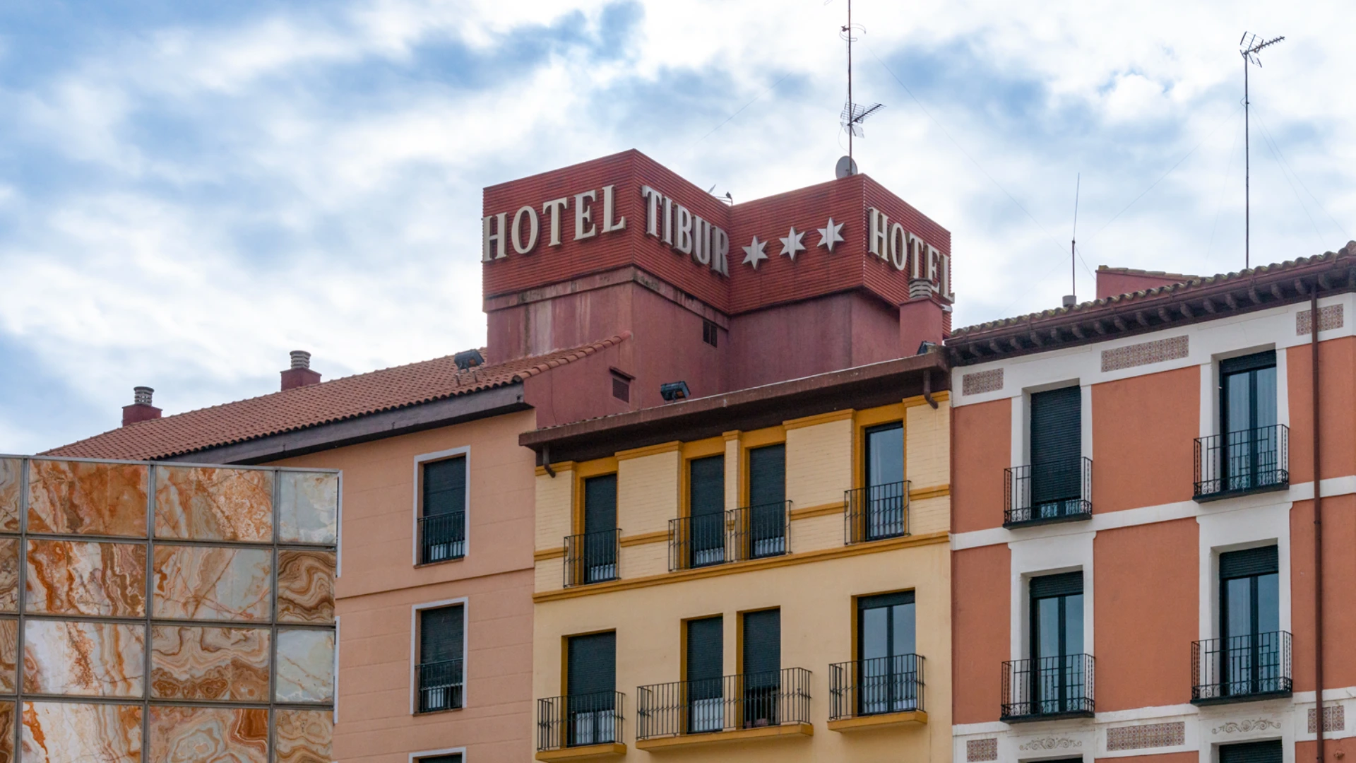 Edificio del Hotel Tibur con cielo nublado, muestra arquitectura tradicional y modernas antenas.