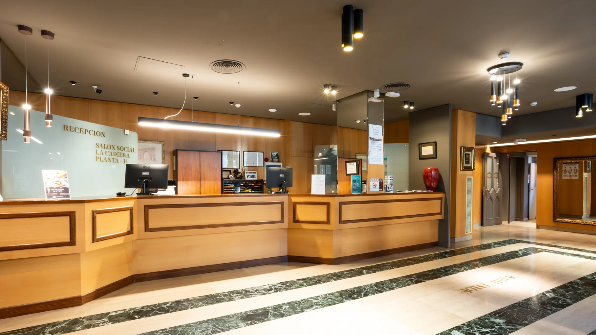 Recepci&oacute;n de hotel con mostrador de madera y decoraci&oacute;n elegante.