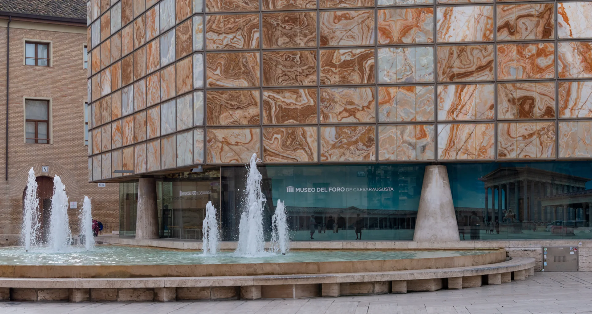 Fachada del Museo del Foro de Caesaraugusta con fuente, arquitectura moderna y paneles marmoleados.