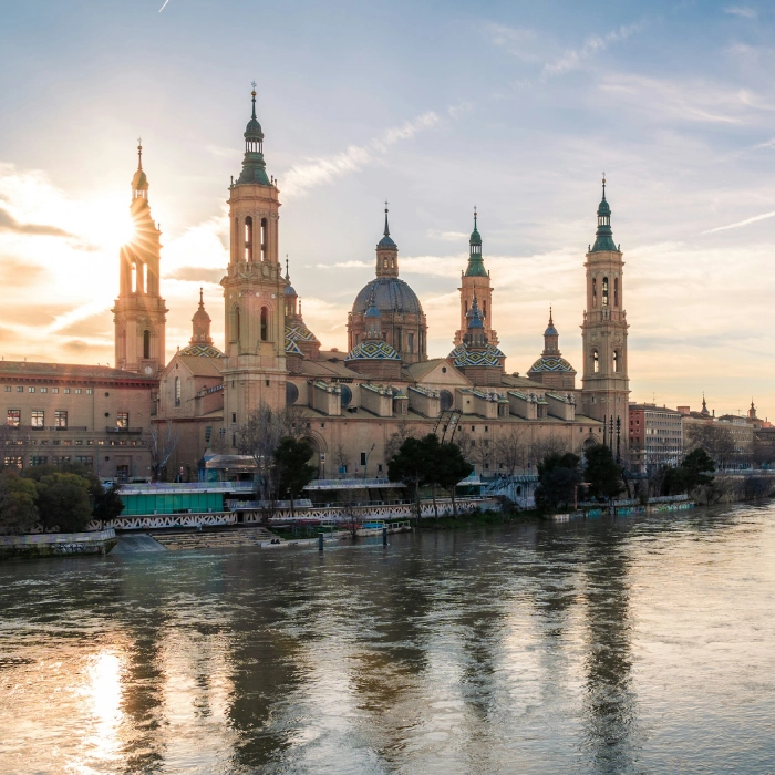 Bas&iacute;lica junto a un r&iacute;o al atardecer, reflejada en el agua.