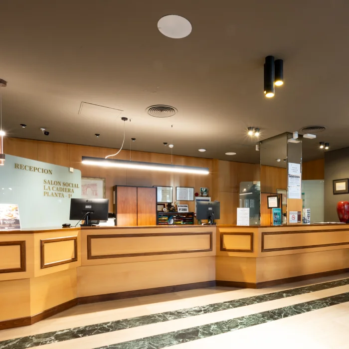 Mostrador de recepci&oacute;n de hotel con computadoras y decoraci&oacute;n moderna.