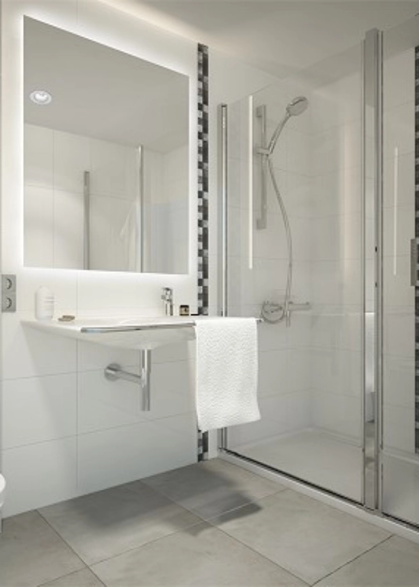 Ba&ntilde;o moderno con espejo iluminado, lavabo, toalla blanca y ducha con mampara de vidrio.