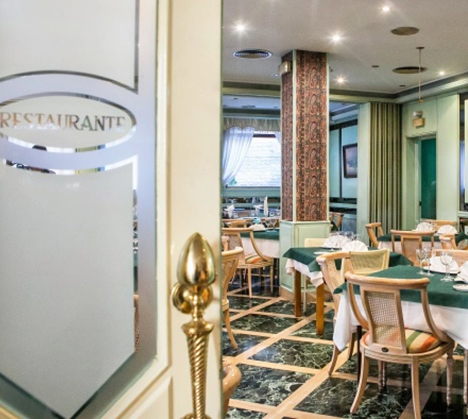 Entrada de cristal a un elegante restaurante con mesas arregladas y sillas de madera.