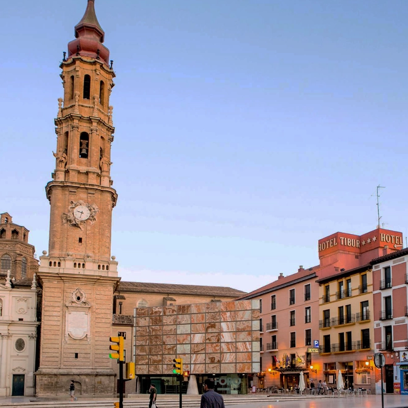 Torre hist&oacute;rica y edificios c&eacute;ntricos con hotel al atardecer.
