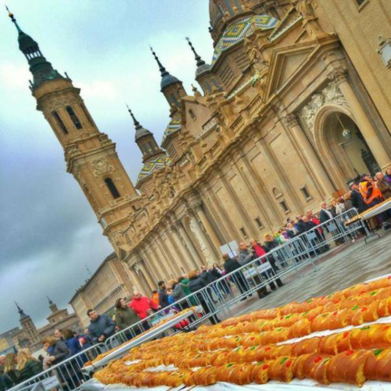 Personas con un gran rosc&oacute;n de Reyes en una plaza frente a un edificio hist&oacute;rico.