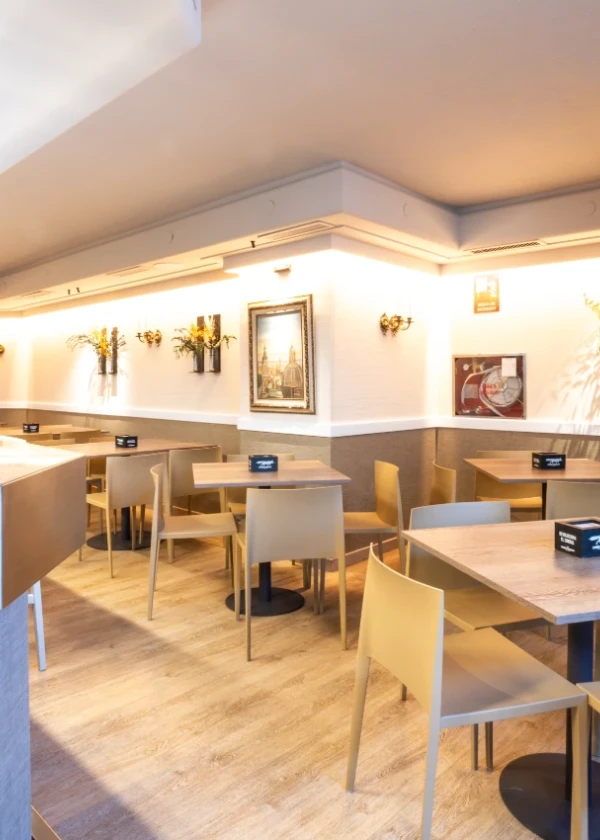 Cafeter&iacute;a moderna y luminosa con sillas y mesas vac&iacute;as.