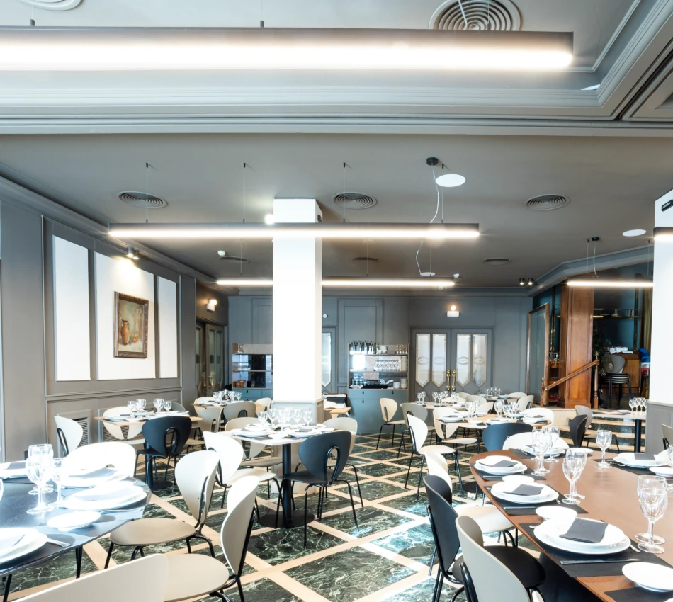 Restaurante elegante con mesas preparadas y suelo de m&aacute;rmol.