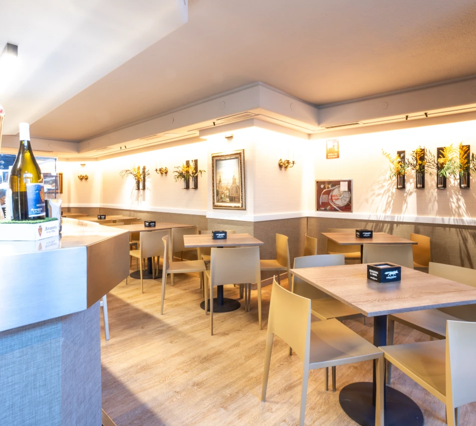 Interior de restaurante moderno con mesas de madera y decoraci&oacute;n de plantas.