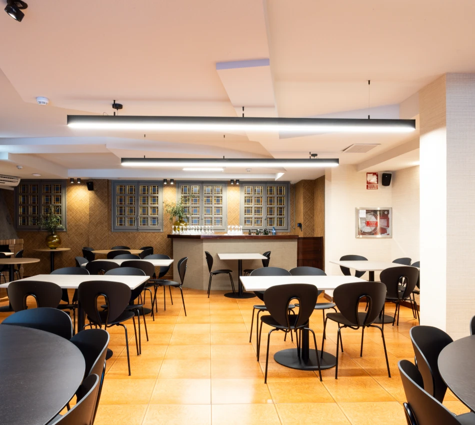 Comedor moderno con mesas redondas y sillas negras.