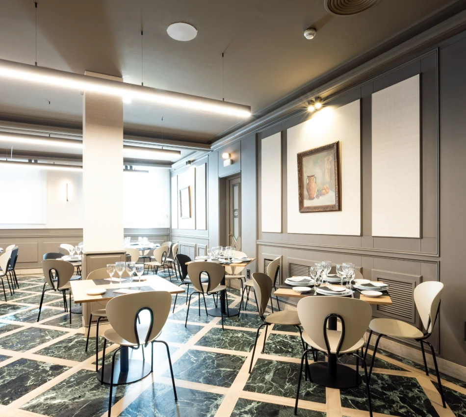 Restaurante moderno con mesas elegantemente dispuestas y obra de arte en la pared.