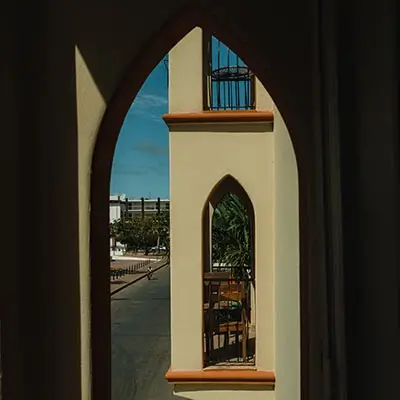 Ventana con forma de arco apuntado, vista de un edificio exterior y cielo azul.