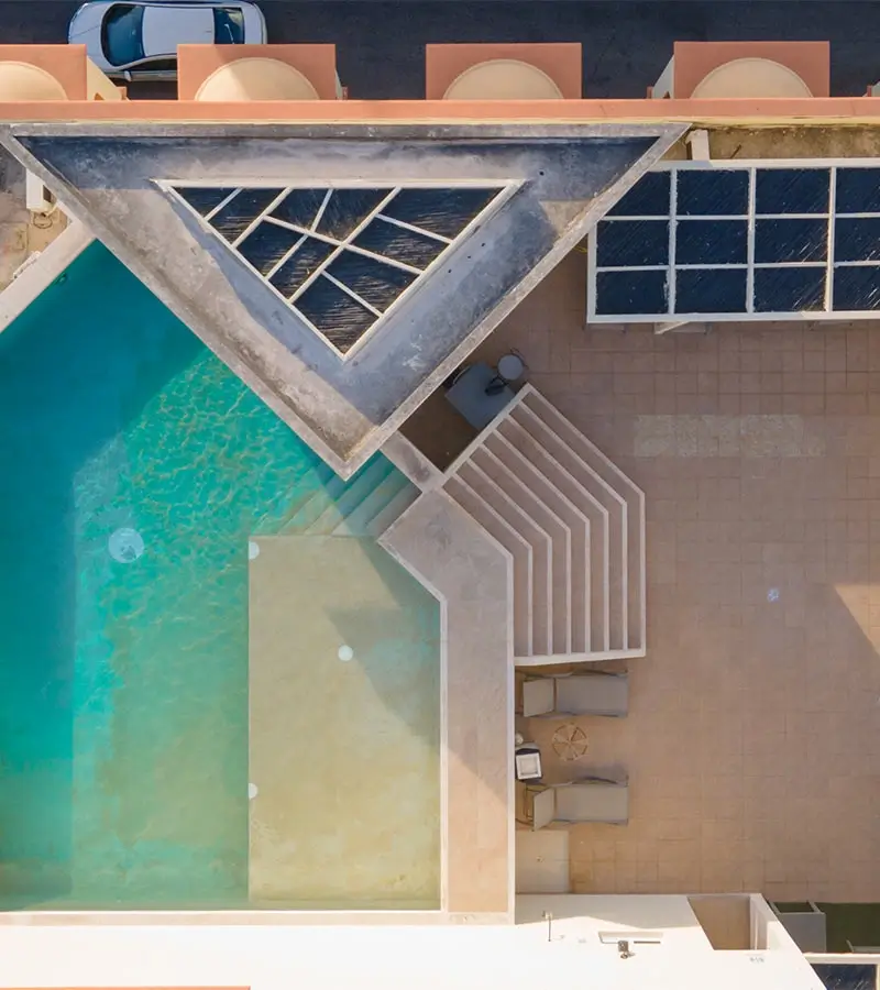 Vista aérea de una piscina triangular con terraza y estructuras angulares modernas.