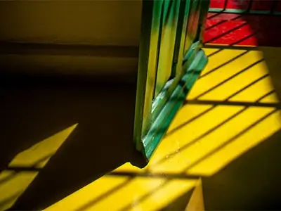 Sombras de rejas proyectadas en el piso amarillo iluminado por la luz del sol.