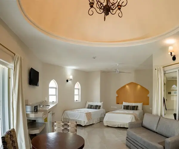 Habitación espaciosa con dos camas, sofá, lámpara colgante y decoración elegante.