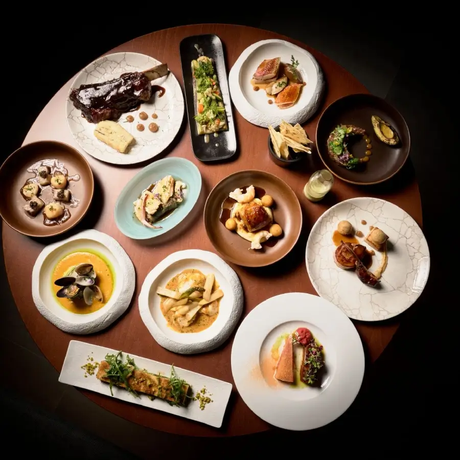 Variedad de platos gourmet sobre una mesa redonda en un ambiente elegante.