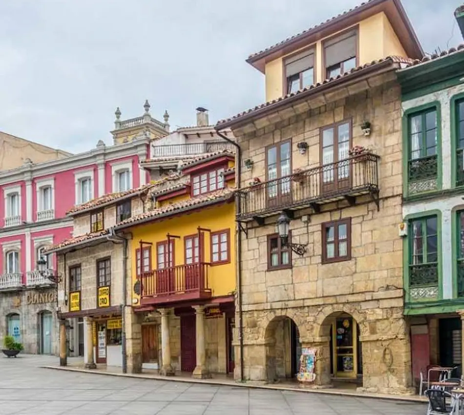 Casas coloridas con balcones en una calle adoquinada, cielo nublado al fondo.
