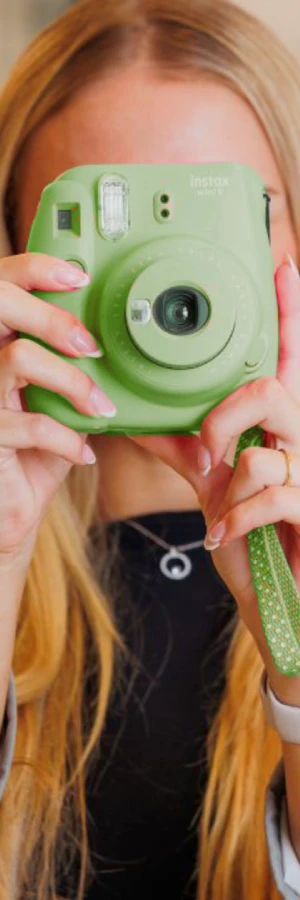 Persona sosteniendo una c&aacute;mara instant&aacute;nea verde.