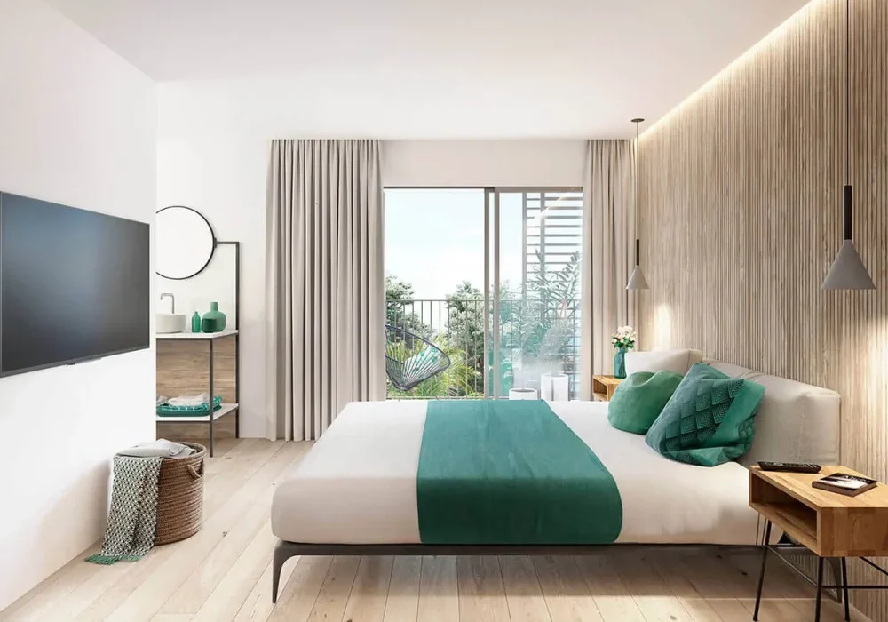 Habitación moderna con cama, televisor, y ventana con vista al exterior, decorada en tonos beige y verde.