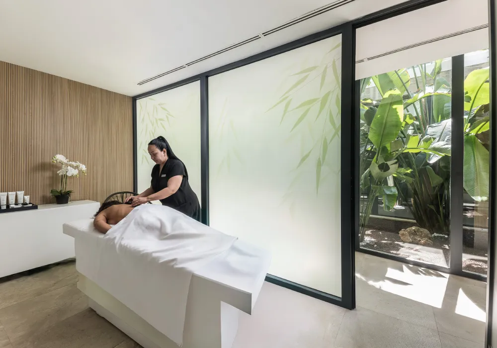 Persona recibiendo un masaje en un ambiente relajante con plantas.