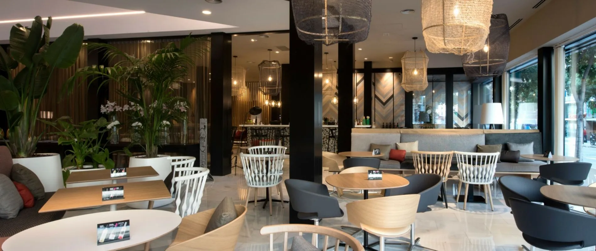 Cafetería moderna con mobiliario elegante y plantas decorativas, ambiente acogedor y luminoso.