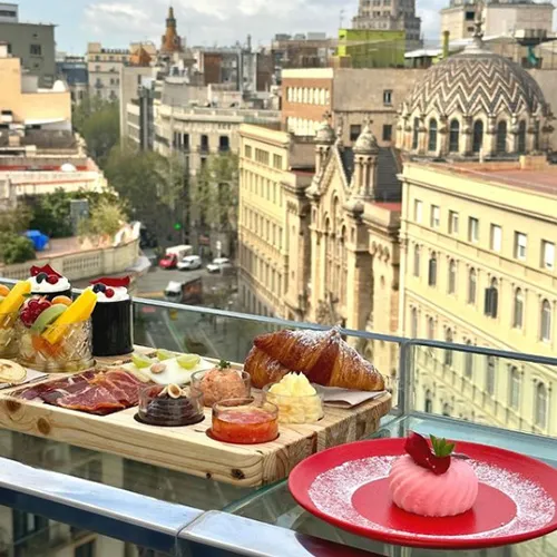 Desayuno gourmet en terraza con vista a ciudad europea.