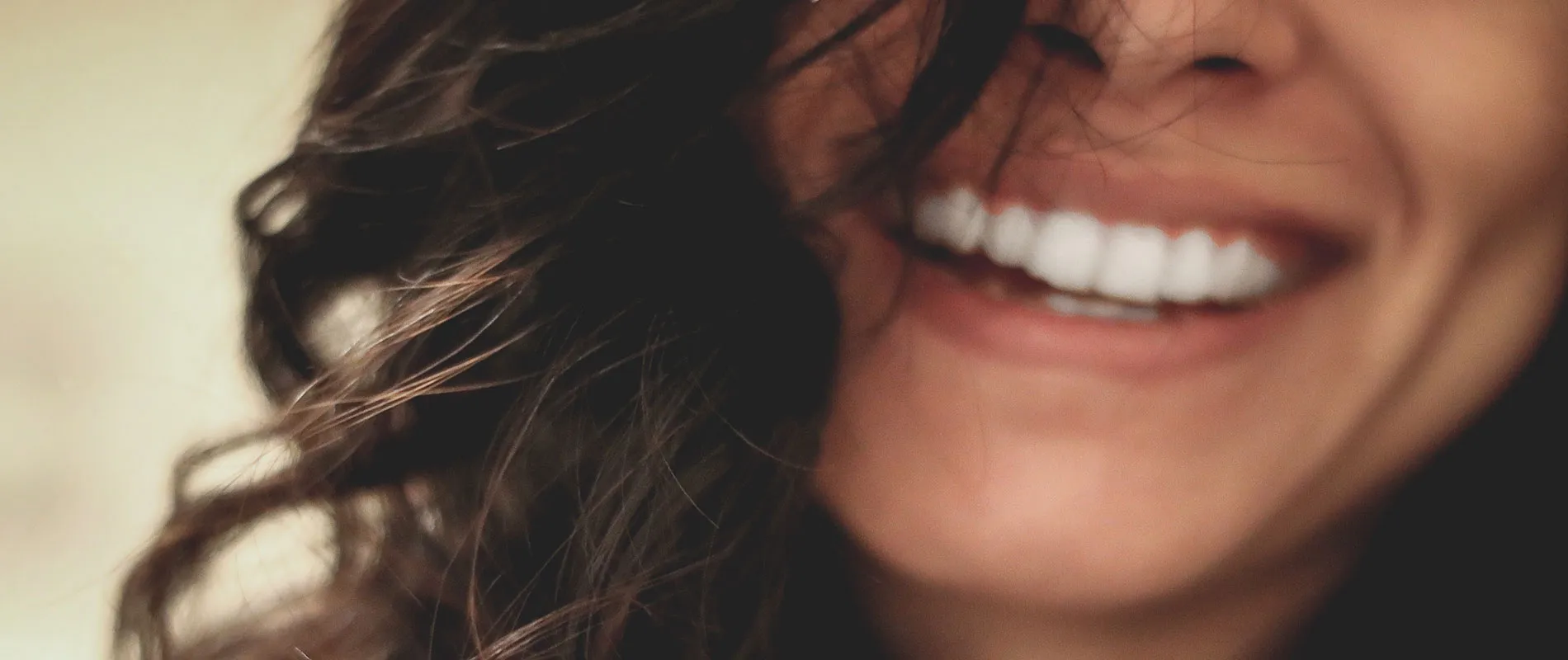 Close-up de una sonrisa con dientes blancos y cabello oscuro desaliñado.