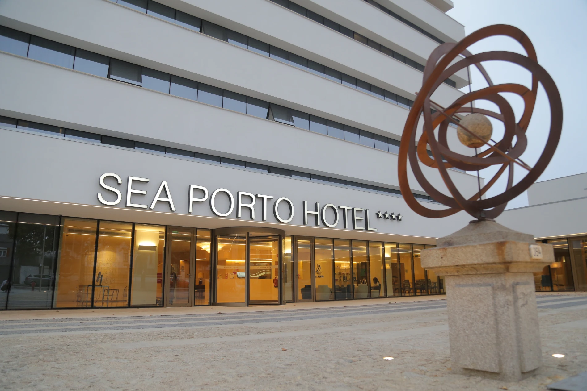 Facade of Sea Porto Hotel with a modern sculpture in the foreground.