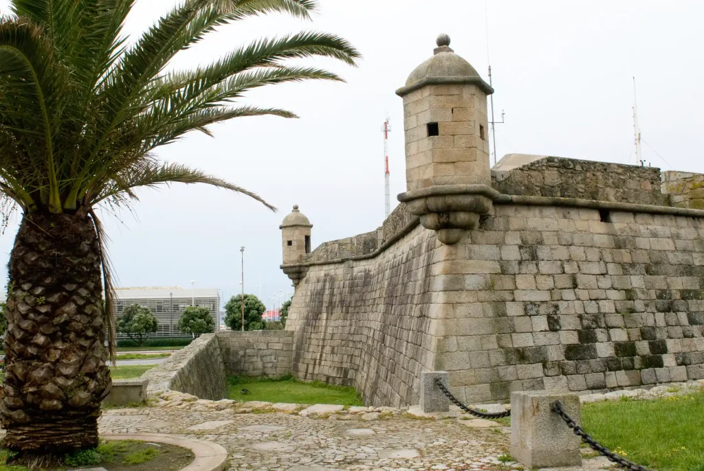 Stone fortress with battlements and watchtower, palm tree in foreground.