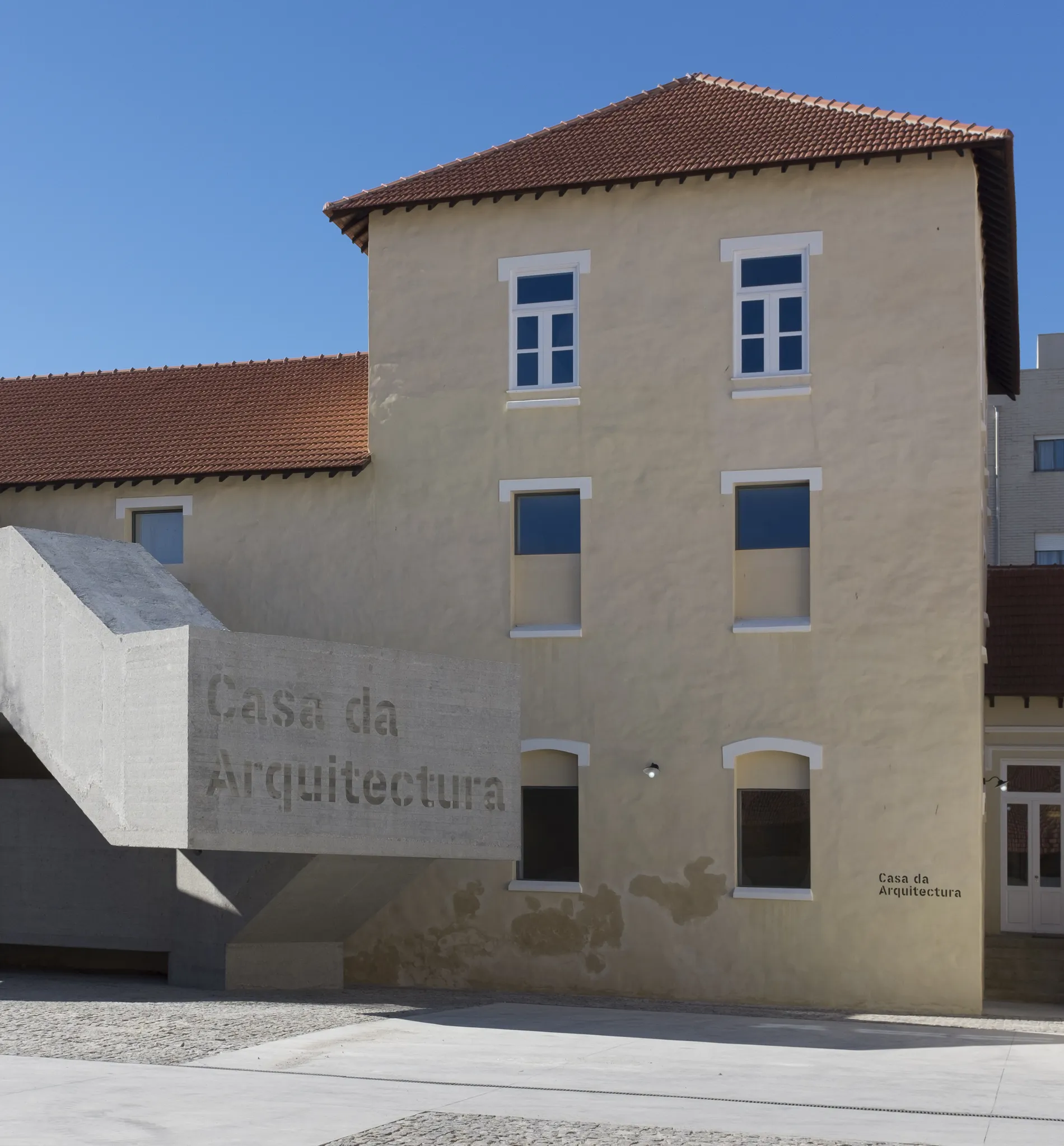 Casa da Arquitectura building with beige walls and red roof under a clear blue sky.