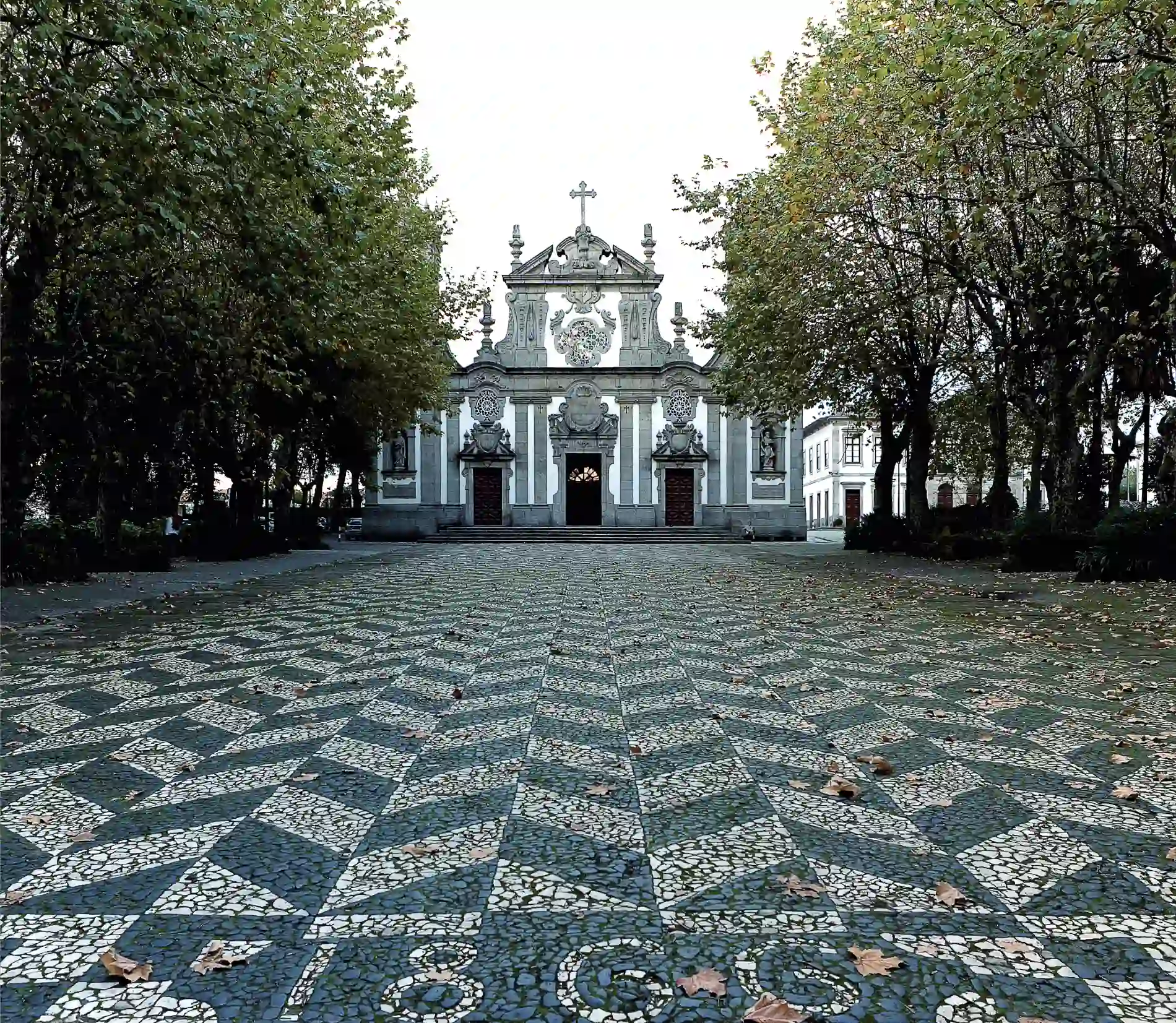 Ornate building with trees and patterned cobblestone path in the foreground.