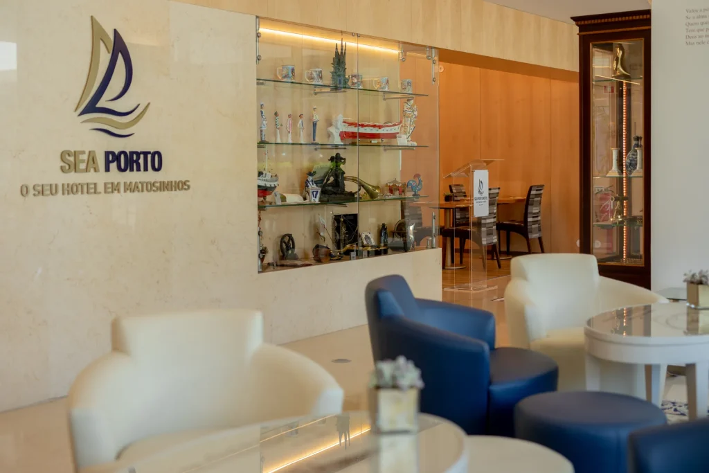 Hotel lobby with blue and white seating, a glass display case, and "Sea Porto" on the wall.
