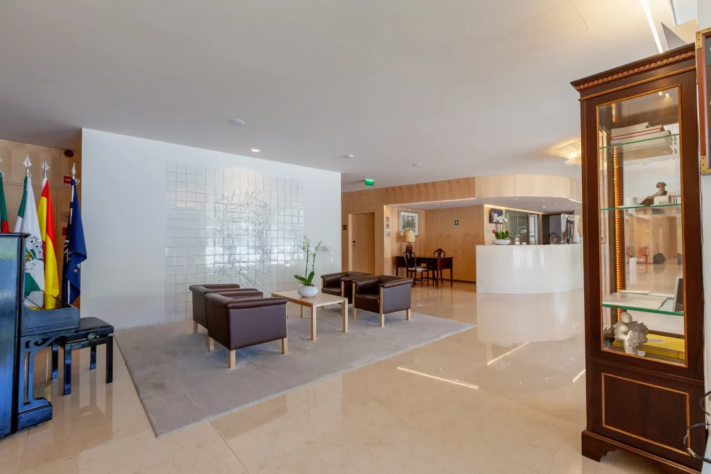 Modern lobby with seating, flags, and a reception desk. Bright, minimalist design.