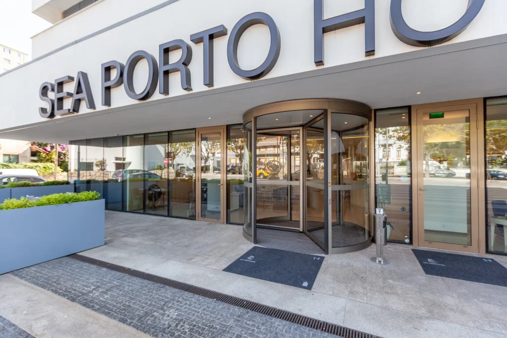 Entrance to Sea Porto Hotel with a revolving glass door and sidewalk view.