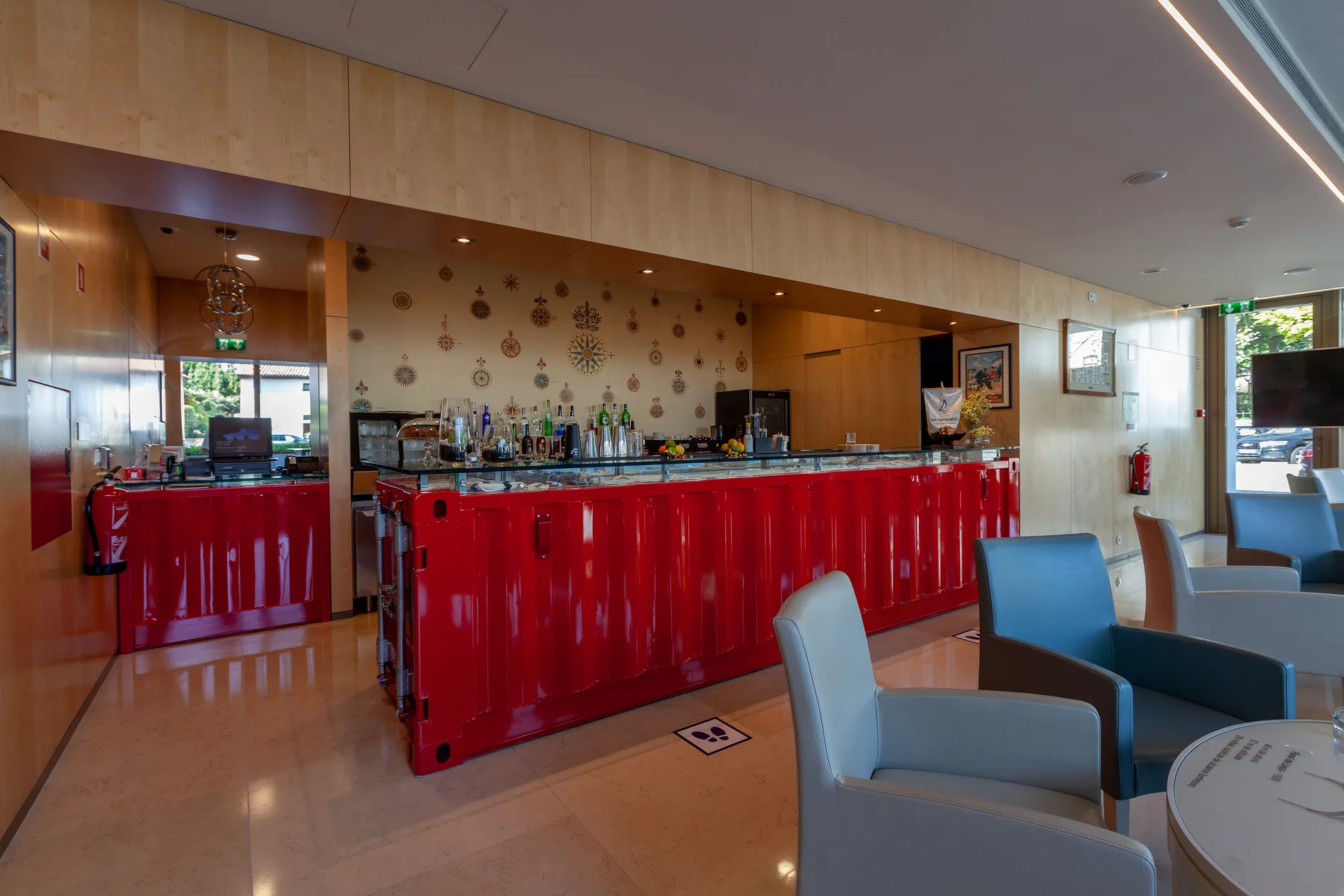 Bar with red counter, modern decor, and seating area with blue and gray chairs.