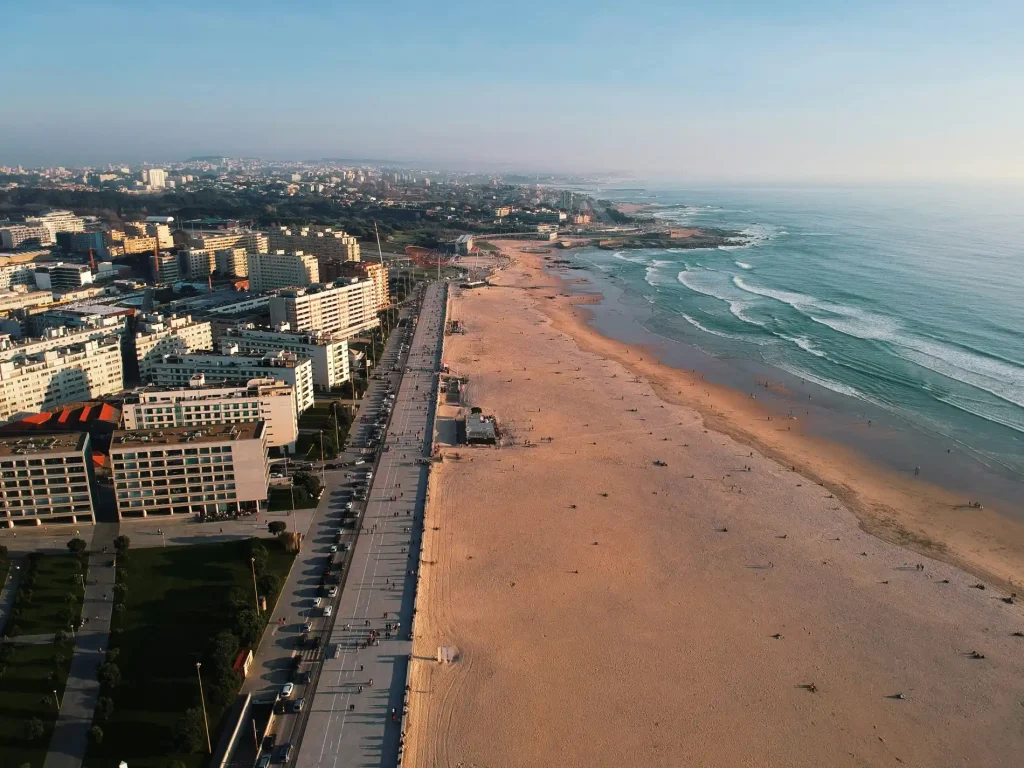 Aerial view of a coastal cityscape with buildings and a sandy beach beside the ocean.