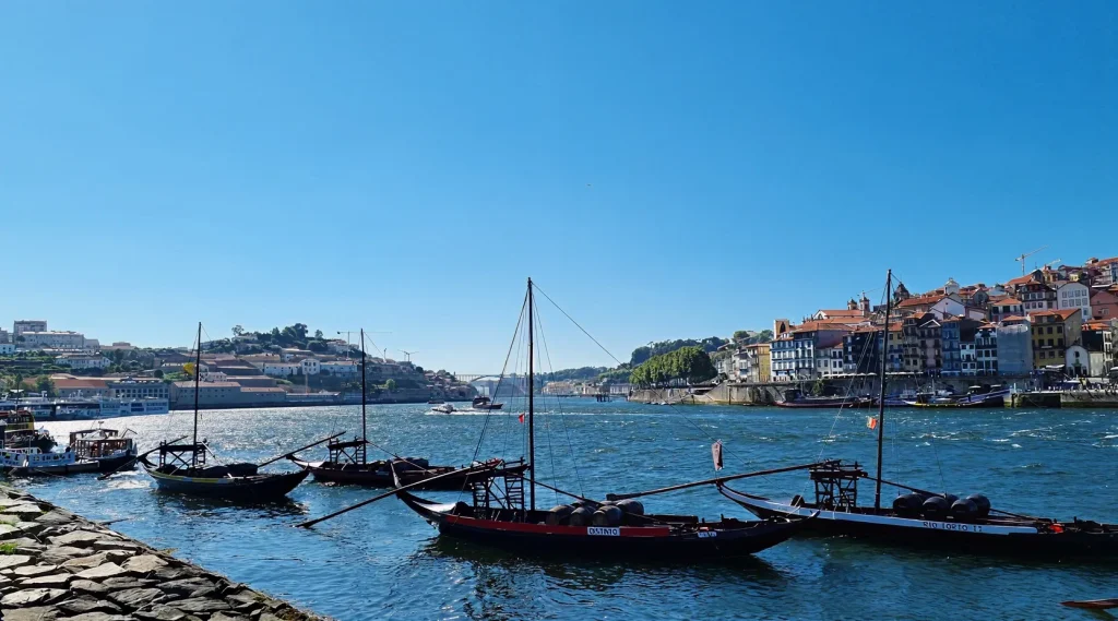 River with traditional boats and colorful buildings under a clear blue sky.