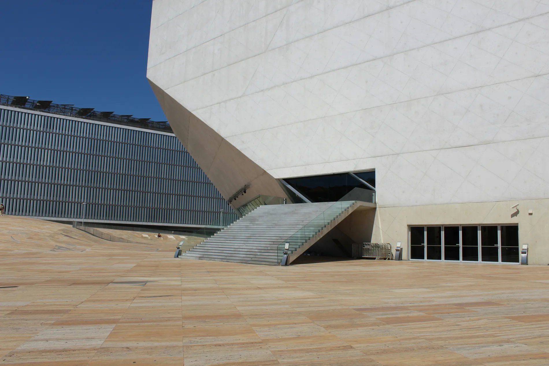 Modern building with geometric shapes and a wide staircase against a blue sky.