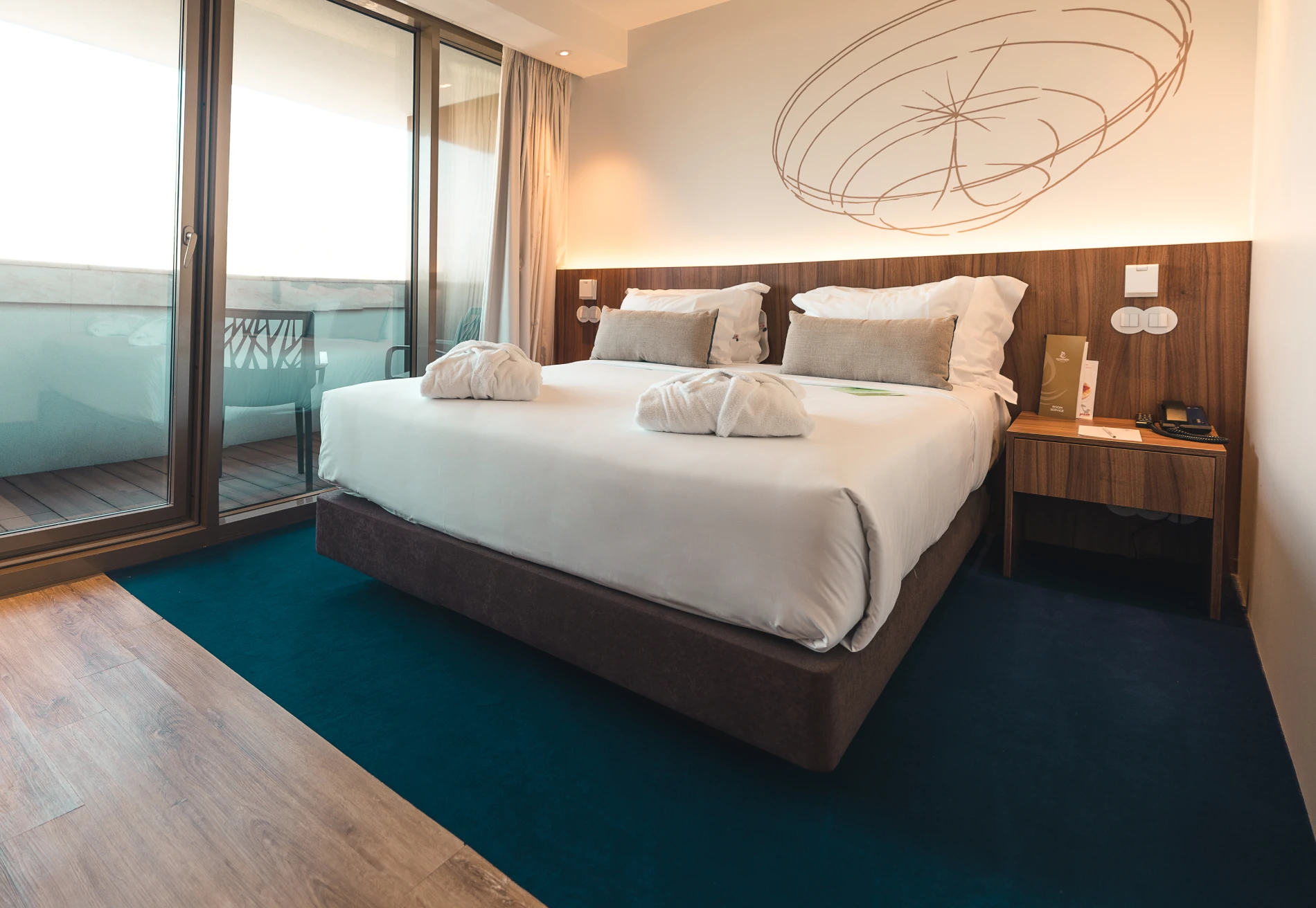 Hotel room with a king-size bed, nightstand, and a balcony view.