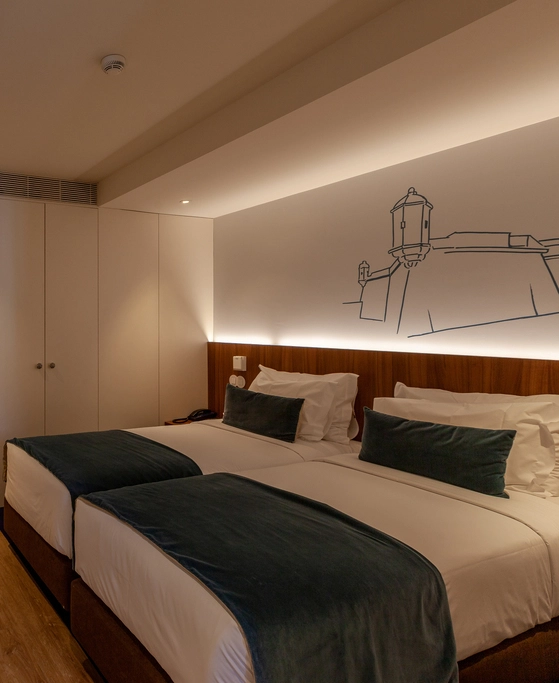 Hotel room with twin beds, teal accents, and wall art of a building sketch.