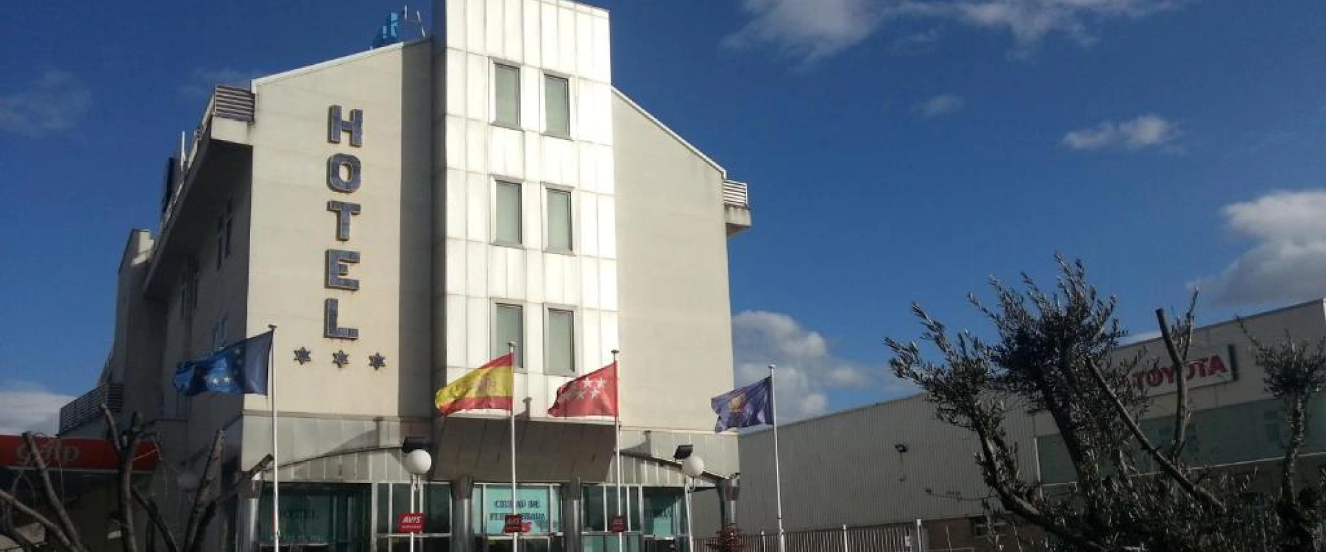 Edificio de hotel con banderas al frente y cielo azul.