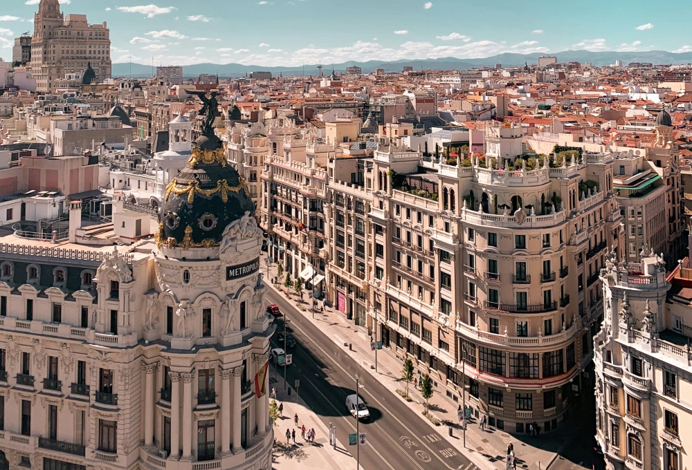 Vista aérea de edificios históricos en un día soleado, con calles transitadas por peatones y autos.