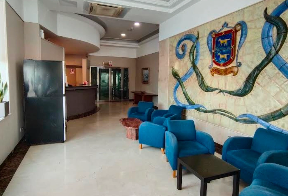 Sala de espera con sillones azules, mural colorido en la pared y recepción de fondo.