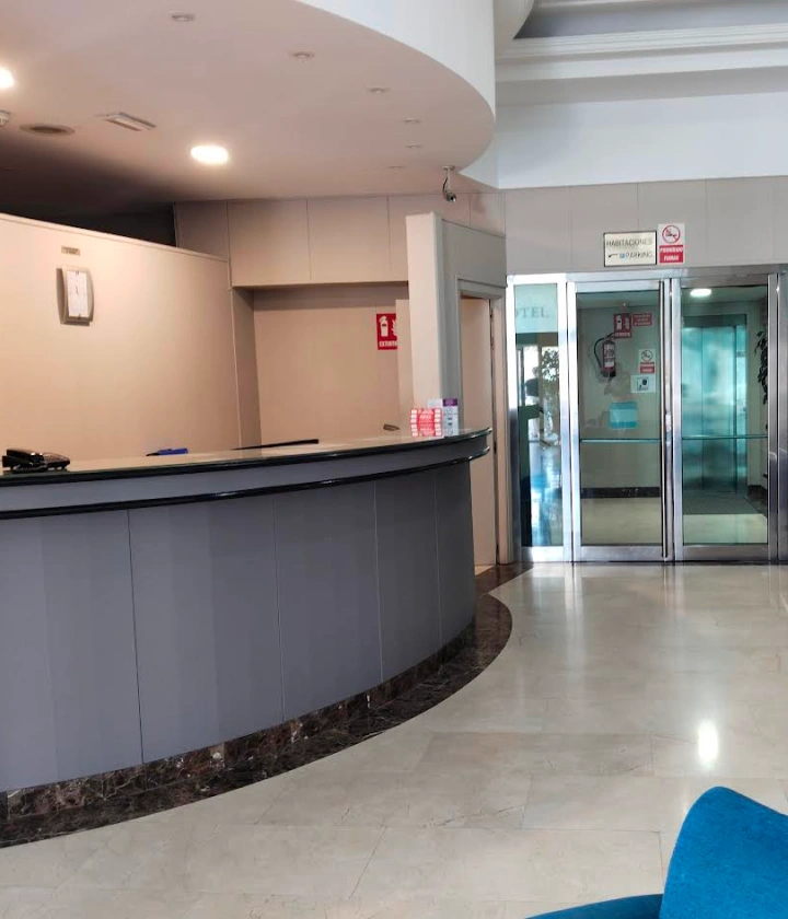 Recepción moderna con mostrador curvo y puerta de cristal al fondo.