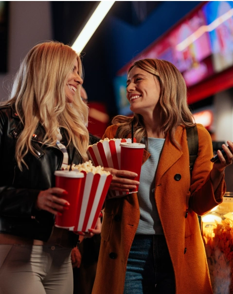 Dos personas sonríen con palomitas de maíz en un cine.