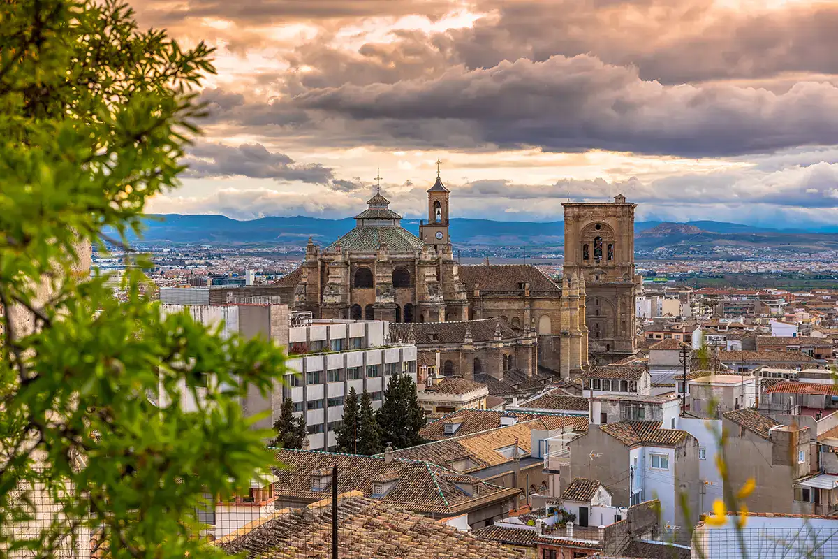 Vista de una catedral y ciudad bajo un cielo nublado al atardecer.