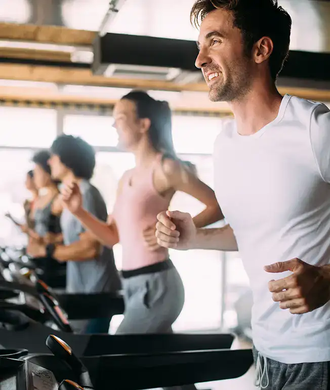 Personas corriendo en cintas en un gimnasio luminoso.