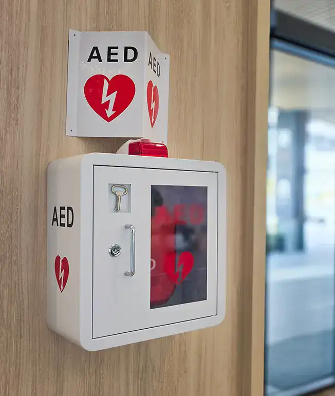 Caja de desfibrilador externo autom&aacute;tico (DEA) en una pared de madera.