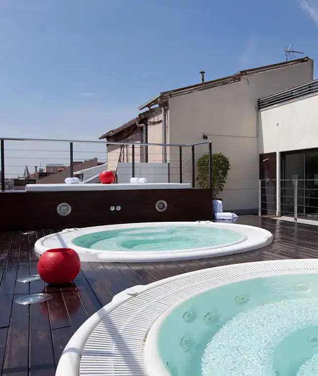 Azotea con dos jacuzzis y una vista urbana bajo el cielo despejado.