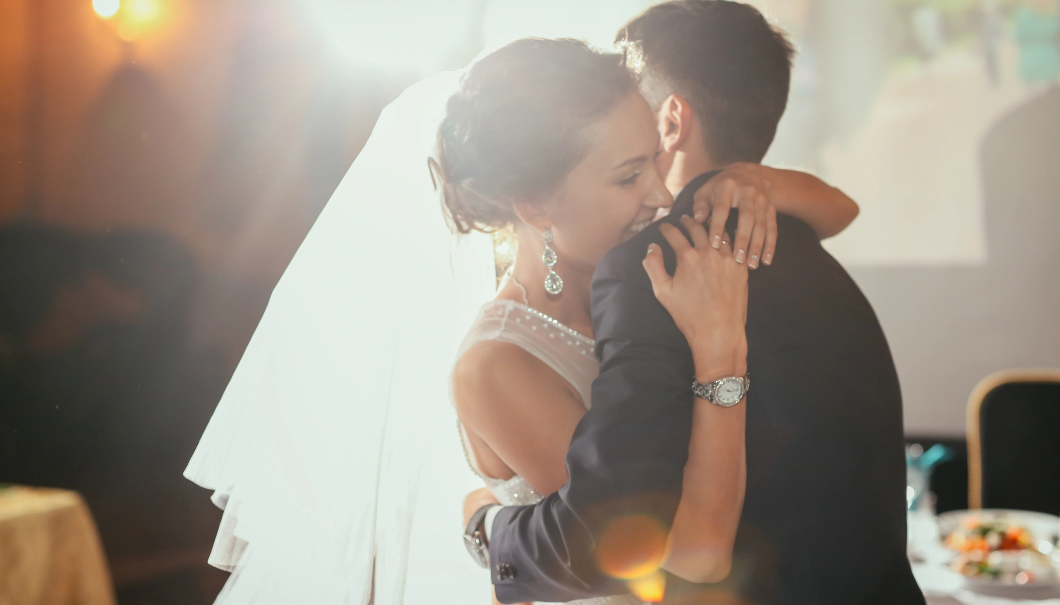 Pareja abraz&aacute;ndose durante su boda, fondo iluminado suavemente.